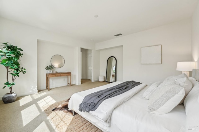 bedroom with light carpet, arched walkways, and visible vents