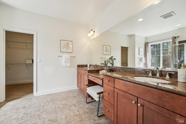 full bathroom with a walk in closet, double vanity, visible vents, and a sink