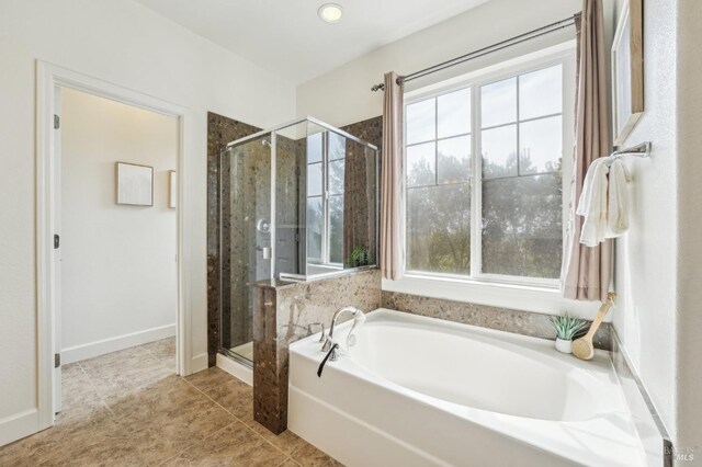 bathroom featuring tile patterned flooring, a bath, and a stall shower