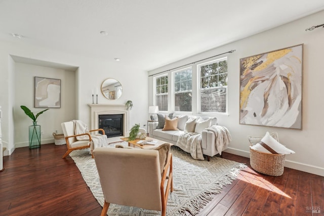 living room featuring baseboards, hardwood / wood-style floors, and a glass covered fireplace