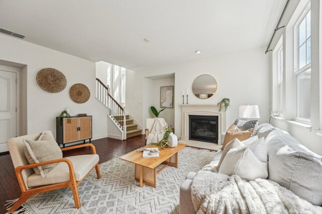 living room featuring visible vents, a glass covered fireplace, wood finished floors, and stairs