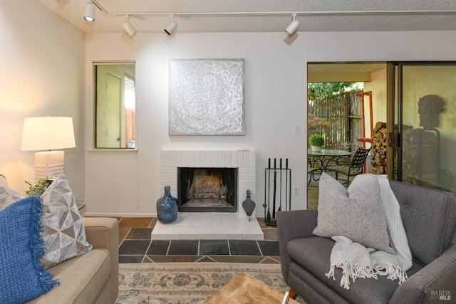 living room featuring baseboards, rail lighting, and a brick fireplace