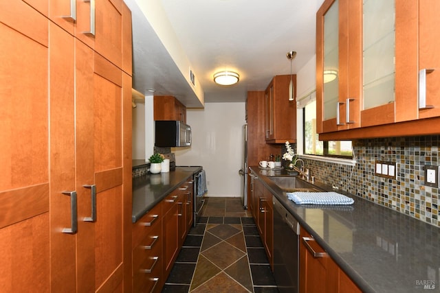 kitchen featuring dark countertops, decorative backsplash, a sink, and appliances with stainless steel finishes