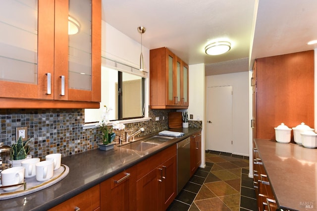 kitchen featuring brown cabinetry, tasteful backsplash, glass insert cabinets, and a sink