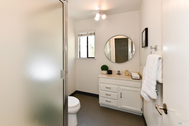 bathroom with a shower stall, vanity, baseboards, and toilet