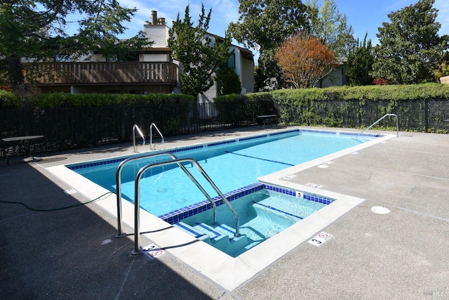 community pool with a patio area, a community hot tub, and fence