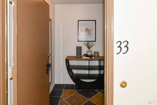 interior space featuring dark tile patterned floors, baseboards, and a textured ceiling
