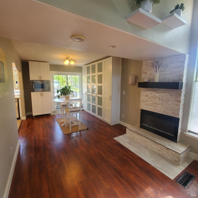 living area with visible vents, baseboards, wood finished floors, and a healthy amount of sunlight