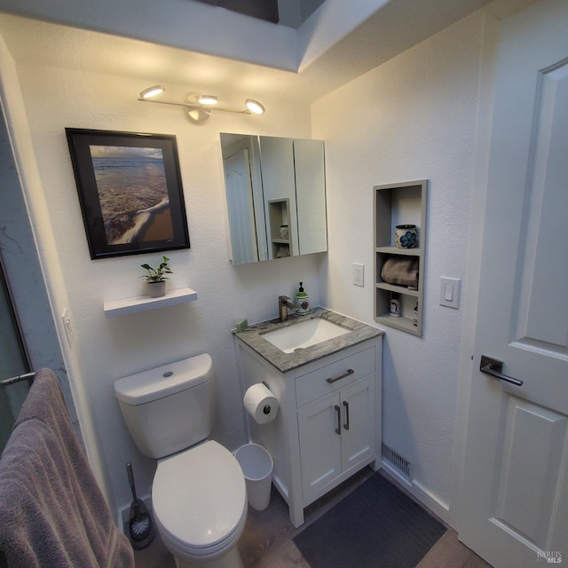bathroom with built in shelves, toilet, vanity, and visible vents
