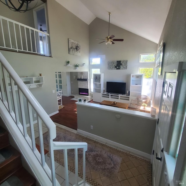 living room with a healthy amount of sunlight, ceiling fan, stairway, and high vaulted ceiling