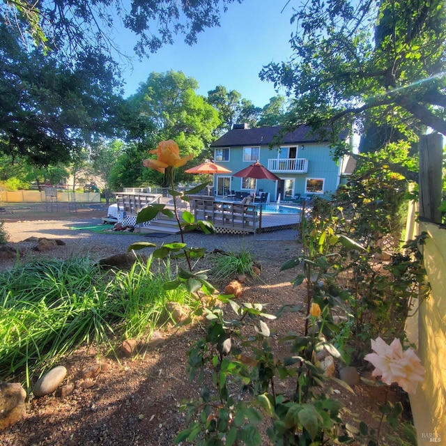view of yard featuring an outdoor pool, fence, a deck, and a balcony