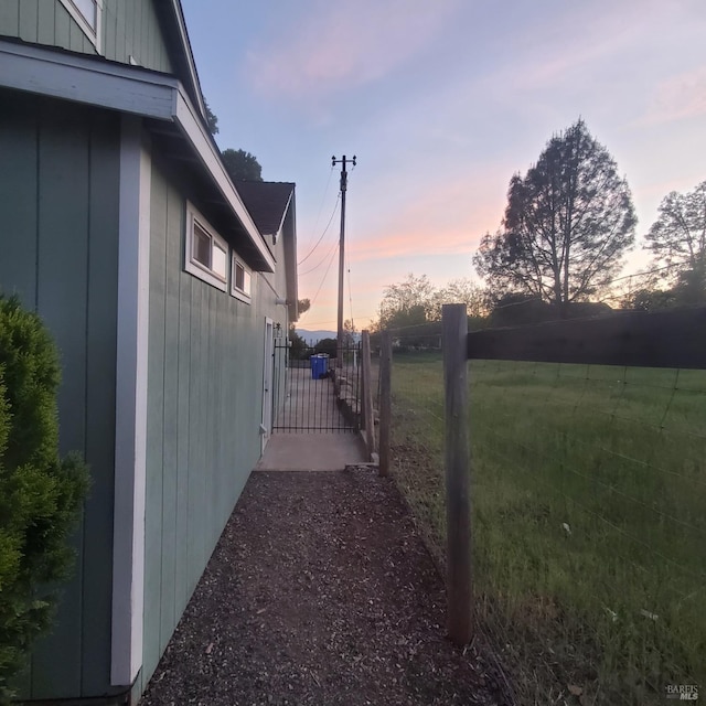 view of side of home with board and batten siding, fence, and a gate
