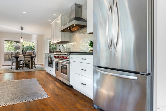 kitchen with white cabinets, wall chimney exhaust hood, appliances with stainless steel finishes, dark wood-type flooring, and decorative backsplash