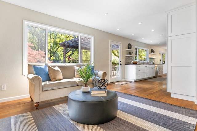 living area featuring recessed lighting, hardwood / wood-style flooring, and baseboards