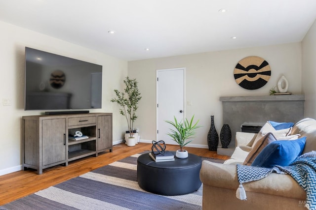 living room with wood finished floors, baseboards, and recessed lighting