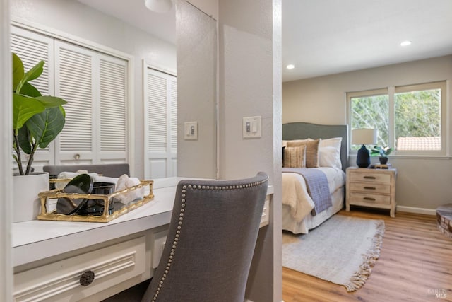 bedroom with baseboards, light wood-type flooring, two closets, and recessed lighting