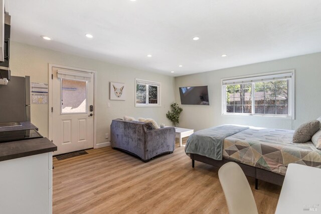 bedroom featuring recessed lighting, light wood-style flooring, and freestanding refrigerator