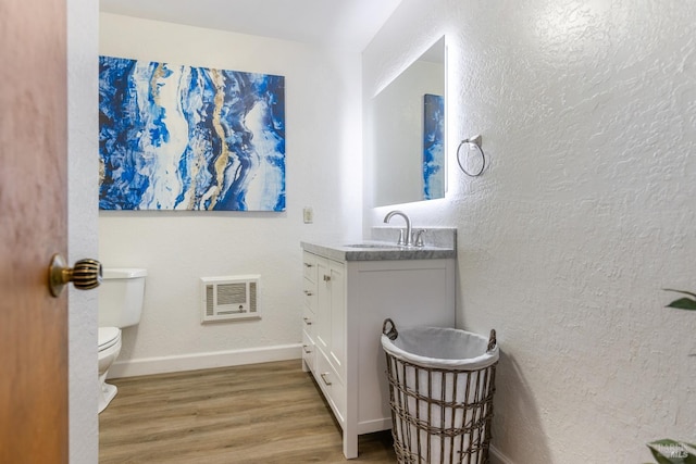 bathroom with vanity, visible vents, toilet, wood finished floors, and baseboards