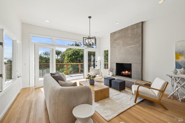 living room with light wood-type flooring, baseboards, an inviting chandelier, recessed lighting, and a fireplace