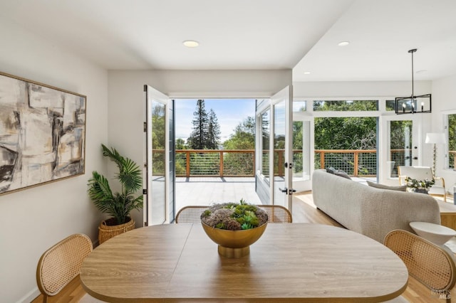 dining area with french doors, wood finished floors, an inviting chandelier, and recessed lighting