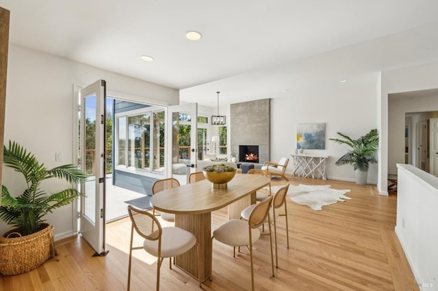 dining space featuring light wood-style flooring, baseboards, a large fireplace, and recessed lighting