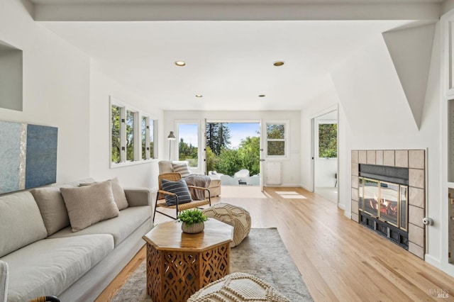 living area with a tile fireplace, recessed lighting, light wood-style floors, and plenty of natural light