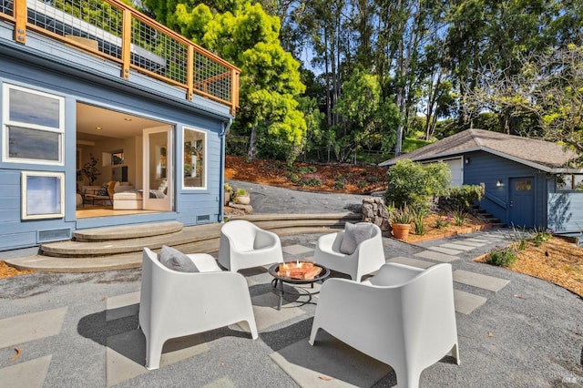 view of patio with an outbuilding, a balcony, and an outdoor fire pit
