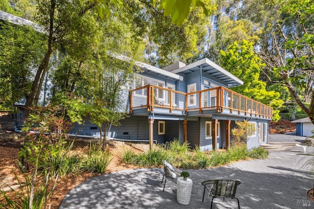 rear view of property with a wooden deck and a patio area