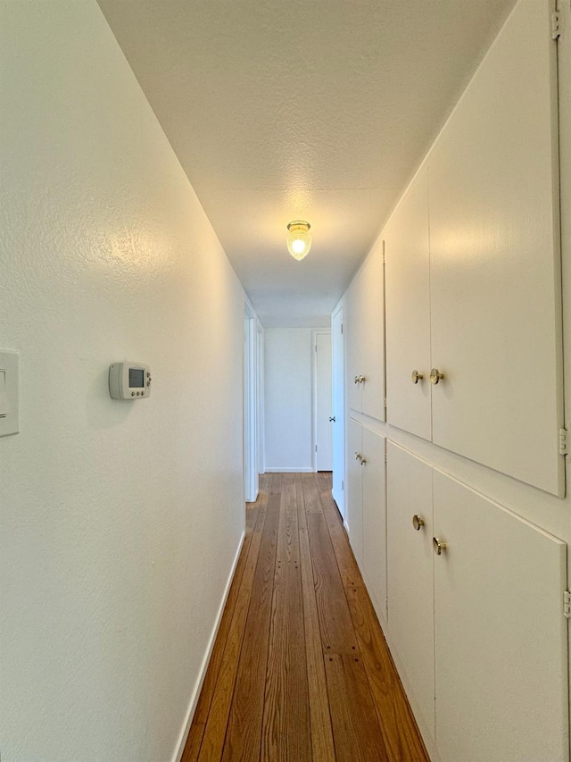 hallway with baseboards and dark wood-type flooring