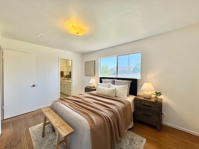 bedroom featuring wood finished floors, connected bathroom, and baseboards