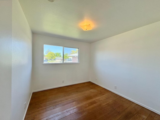 empty room featuring baseboards and hardwood / wood-style flooring
