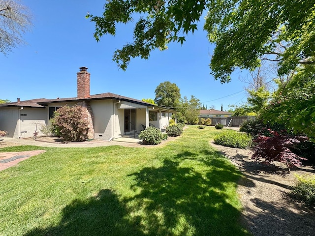 exterior space featuring a chimney, fence, stucco siding, and a front yard