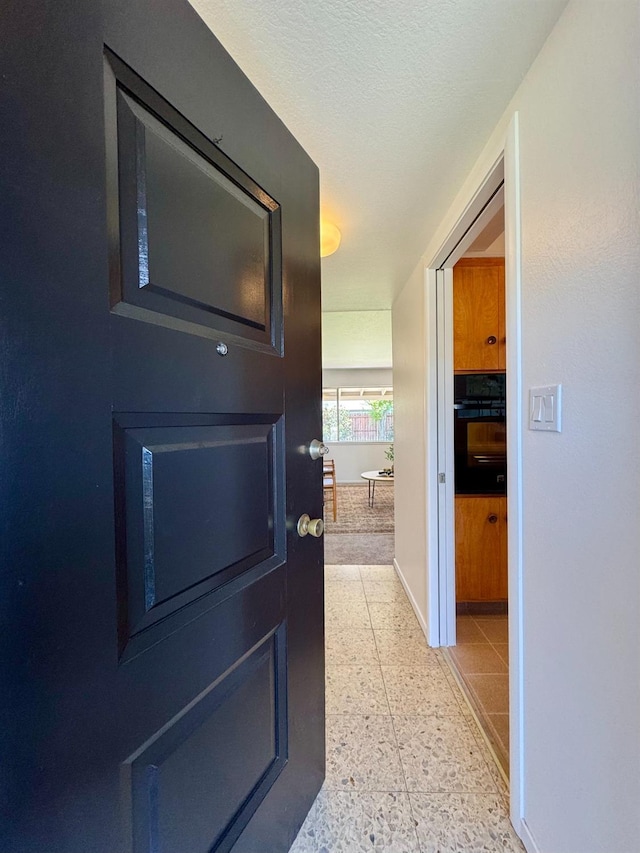 hall featuring baseboards and light speckled floor
