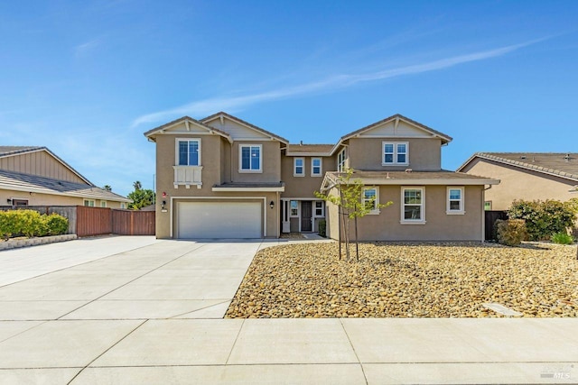 view of front facade with concrete driveway, stucco siding, fence, and a garage