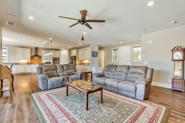 living area with visible vents, a wealth of natural light, light wood finished floors, and ceiling fan