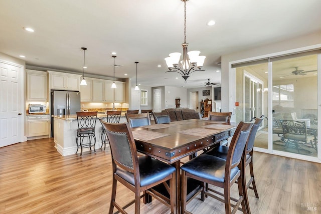dining area featuring recessed lighting, light wood-type flooring, ceiling fan with notable chandelier, and a toaster