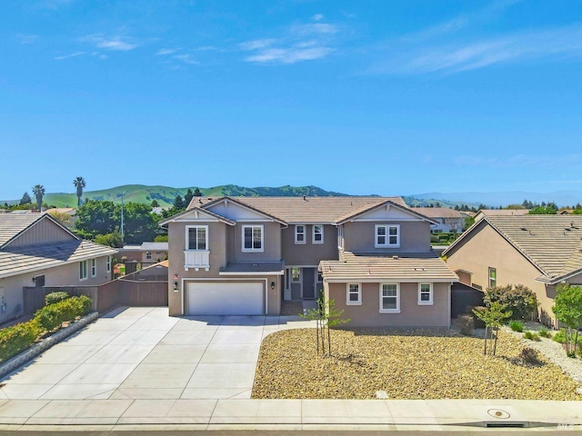 view of front of house with concrete driveway, stucco siding, a mountain view, a tile roof, and a garage