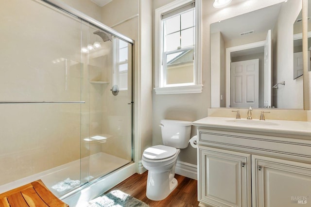 bathroom featuring baseboards, toilet, vanity, wood finished floors, and a stall shower
