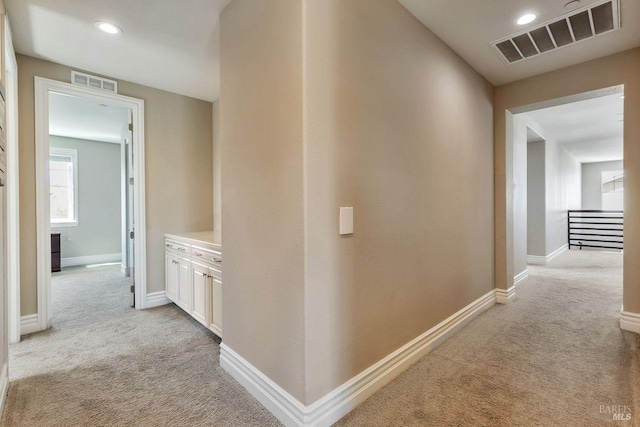 hallway with visible vents, recessed lighting, and light colored carpet