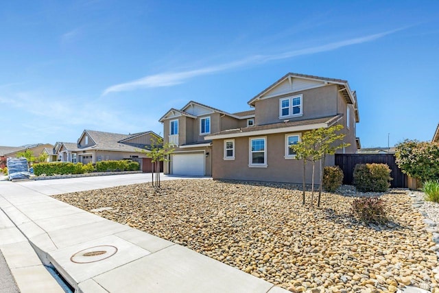 view of front of property with driveway, stucco siding, fence, and a garage