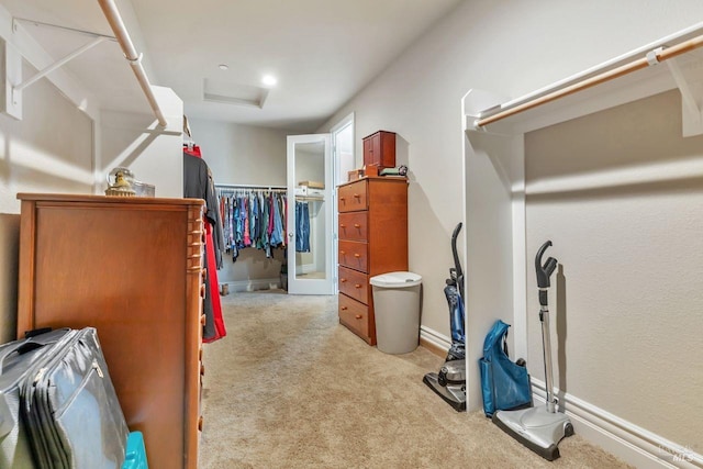 walk in closet with light carpet and attic access