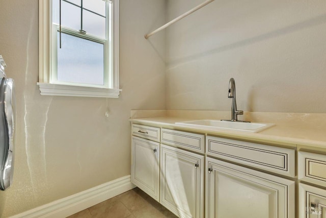 washroom with light tile patterned floors, baseboards, a sink, and cabinet space