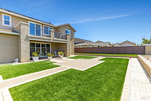 view of yard featuring a patio, a balcony, and a fenced backyard