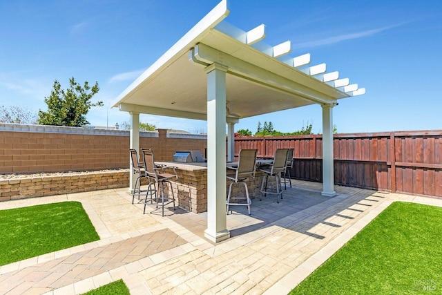 view of patio with a fenced backyard, outdoor dry bar, and area for grilling