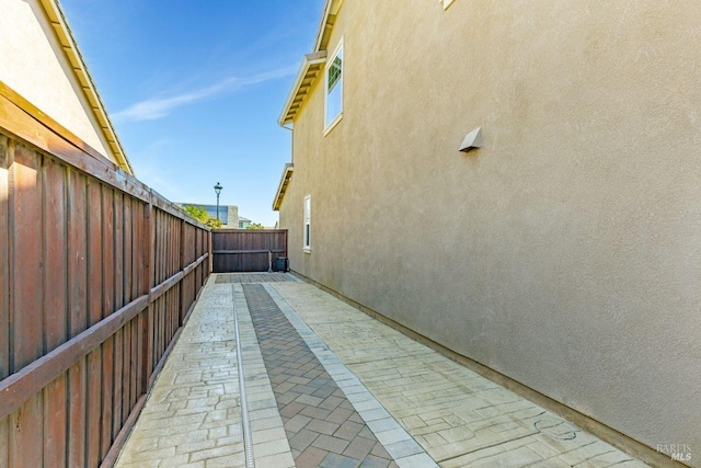 view of side of property featuring a patio, stucco siding, and fence