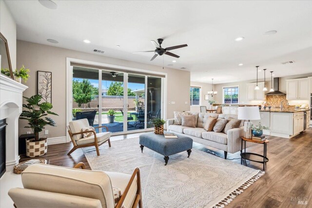 1012 Capitola Ct, Vacaville, CA 95687 - living room with ceiling fan, wood finished floors, a chandelier, a glass covered fireplace, and recessed lighting