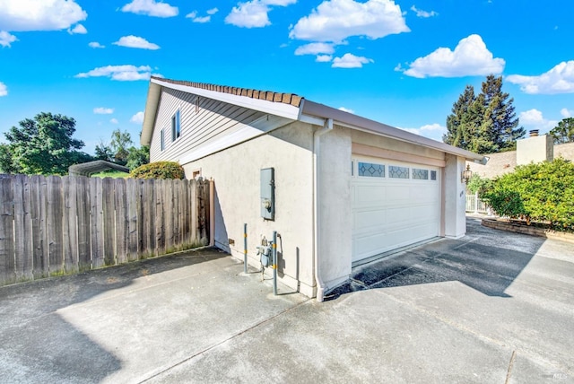 410 Duvall Ct, Benicia, CA 94510 - view of side of home featuring concrete driveway, stucco siding, fence, and an attached garage