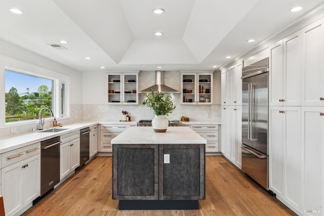 kitchen featuring a sink, wall chimney exhaust hood, visible vents, backsplash, and appliances with stainless steel finishes