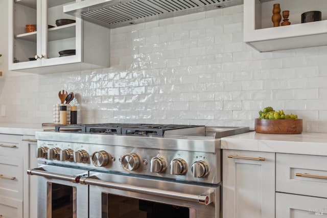kitchen with tasteful backsplash, range with two ovens, glass insert cabinets, and custom range hood