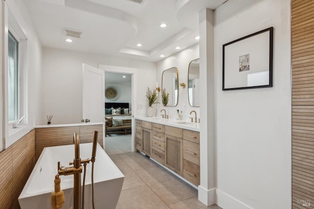 bathroom with a soaking tub, double vanity, recessed lighting, and a sink